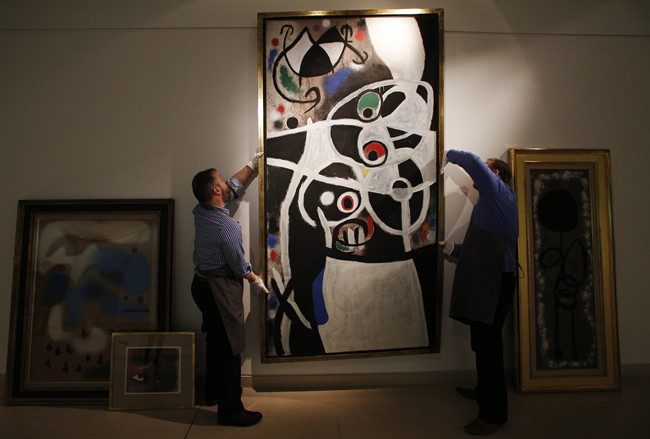 Auction house workers adjust Joan Miro's 1968 oil painting "Women and Birds" which has an estimated sale price of up to $11.5 million.