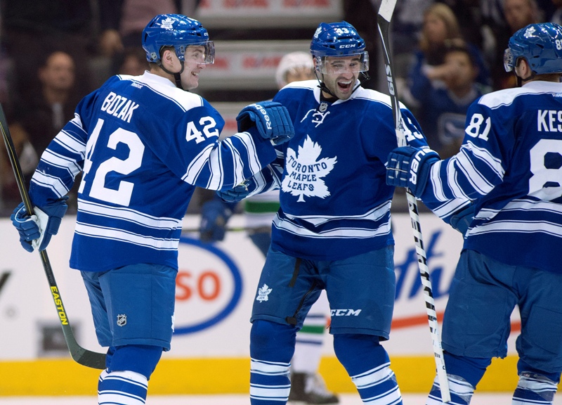 Toronto Maple Leafs' Tyler Bozak (left) and Nazem Kadri (centre) congratulate Phil Kessel on his game winning goal during third period NHL action against the Vancouver Canucks in Toronto on Saturday February 8, 2014. THE CANADIAN PRESS/Frank Gunn.