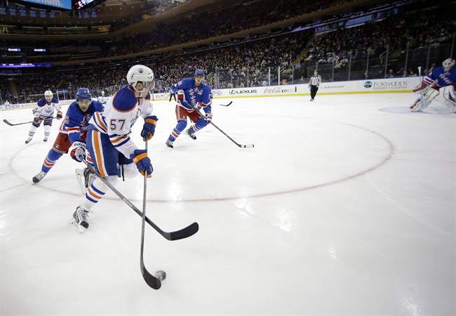 New York Rangers' Derick Brassard (16) chases Edmonton Oilers' David Perron (57) for control of the puck during the first period of an NHL hockey game on Thursday, Feb. 6, 2014, in New York. 