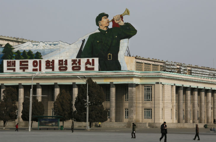 North Korean walk under a sign of a soldier blowing a bugle at Kim Il Sung Square in Pyongyang, North Korea, Tuesday, Feb. 18, 2014.