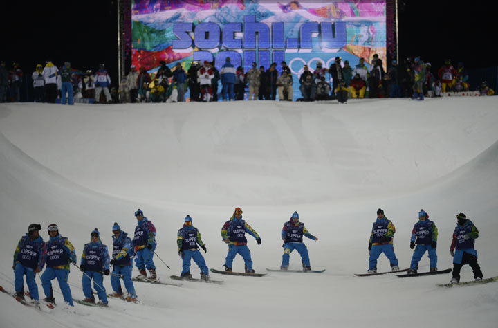Volunteers check the condition of the half pipe before a Men's Snowboard Halfpipe training session at the Rosa Khutor Extreme Park during the Sochi Winter Olympics on February 9, 2014. 