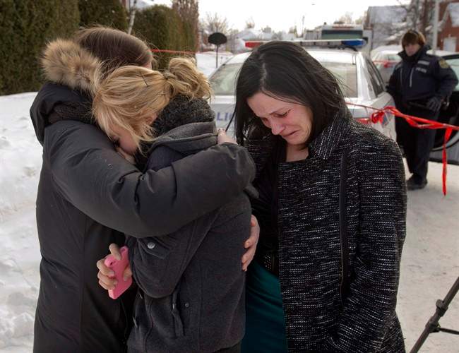 Friends of three people who were found dead in a home comfort each other Tuesday, February 11, 2014 in Trois Rivieres, Que.