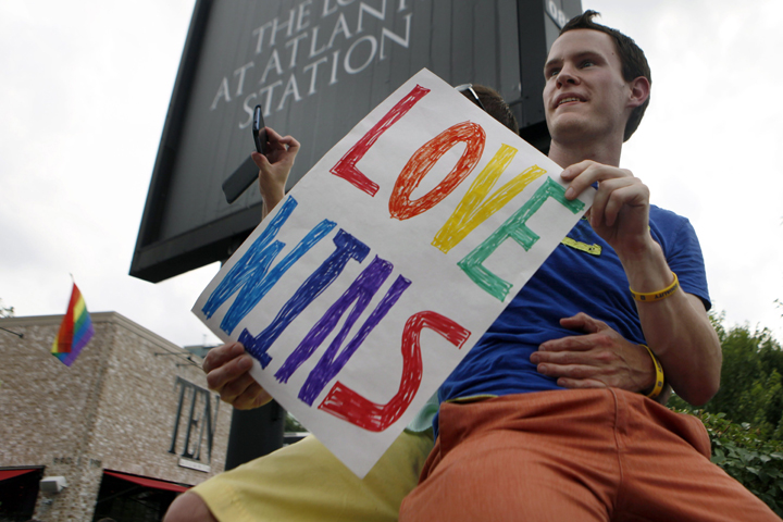 In this June 26, 2013 file photo, Daniel Hicks sits on a pillar with his boyfriend to watch the local crowd celebrate the U.S. Supreme Court's rulings on two landmark gay rights cases surrounding same-sex marriage, in Atlanta.