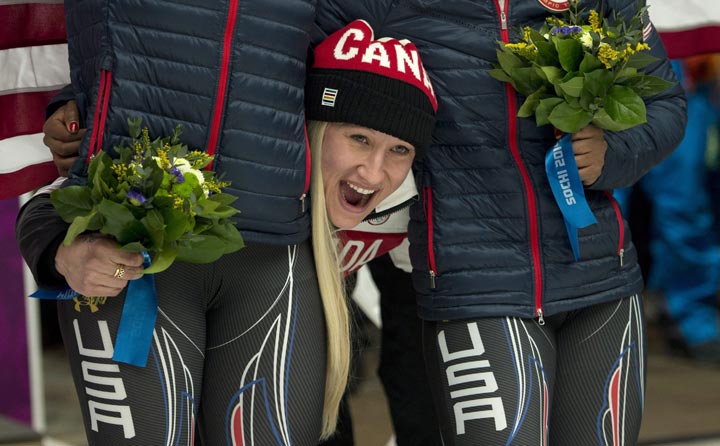Canada's Kaillie Humphries pokes her head between the silver medallists from the USA after she and Heather Moyse won the gold medal in women's bobsled at the Sochi Winter Olympics in Krasnaya Polyana, Russia, Wednesday, Feb. 19, 2014. 