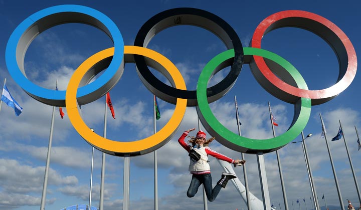 A woman jumps for a picture under the Olympic rings on February 6, 2014. (Andrej Isakovic/AFP/Getty Images)