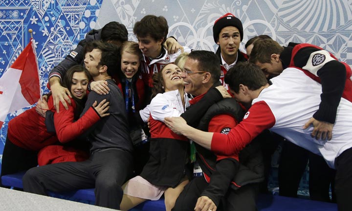 Canada’s Meagan Duhamel, centre, and Eric Radford, second from left, are embraced by fellow team members after receiving their results for the team pairs short program figure skating competition at the Iceberg Skating Palace during the 2014 Winter Olympics, Thursday, Feb. 6, 2014, in Sochi, Russia. (AP Photo/Darron Cummings)
