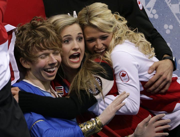 Kevin Reynolds of Canada, left, and team members react as he sits in the results area after competing in the men’s team free skate. (AP Photo/David J. Phillip )