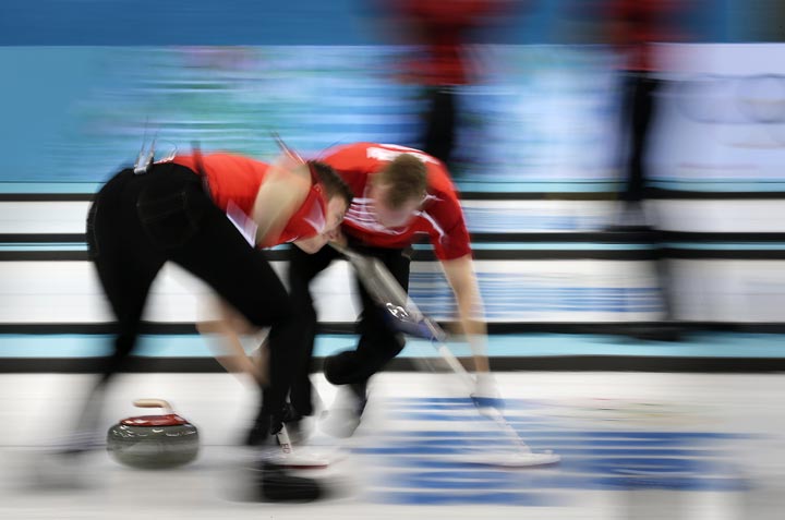 Denmark's Troels Harry, left, and Mikkel Poulsen sweep the ice during the men's curling competition against Russia at the 2014 Winter Olympics, Monday, Feb. 10, 2014, in Sochi, Russia. 