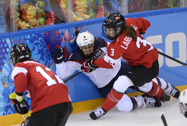 Canada’s Jocelyne Larocque (R) hits US Megan Bozek during the Women’s Ice Hockey Group A match Canada vs USA at the Shayba Arena during the Sochi Winter Olympics on February 12, 2014. (Jonathan Nackstrand/AFP/Getty Images)
