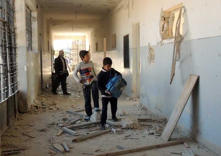 Syrian children search for their belongings at a school following airstrikes by Syrian government forces on December 22, 2013 in the northern Syrian city of Marea on the outskirts of Aleppo.