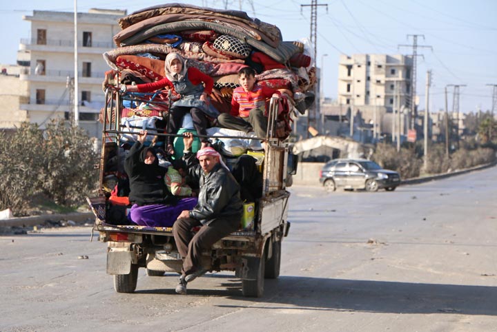 Syrians sit at the back of a truck loaded with belongings as they leave for a safer area on February 18, 2014 in the northern Syrian city of Aleppo. 