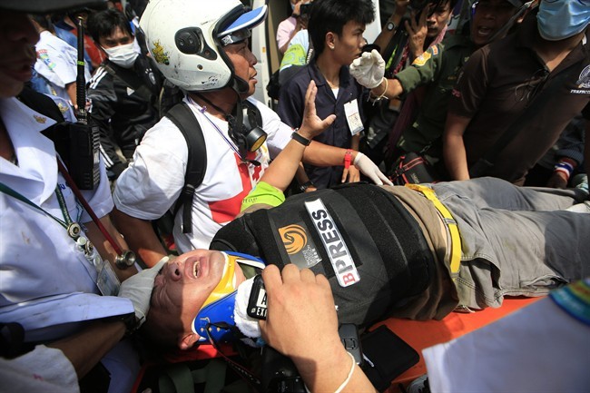 An injured foreign reporter is carried by medic team to an ambulance during a clash between police force and anti-government protesters Tuesday, Feb. 18, 2014 in Bangkok, Thailand.