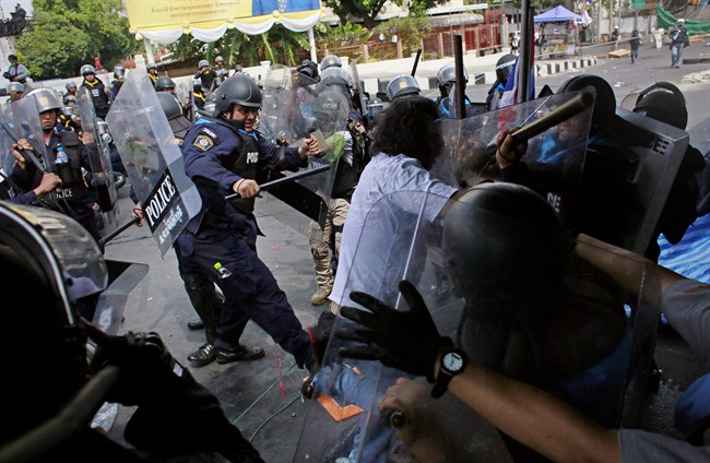 Riot police beat an anti-government protester during a clash in Bangkok, Thailand, Tuesday, Feb. 18, 2014. Attacks on weekend protests killed a child and left dozens injured.