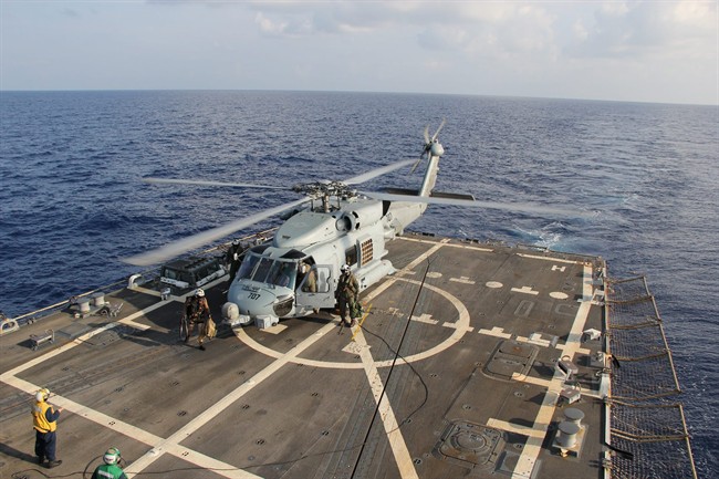 A U.S. Navy helicopter lands aboard Destroyer USS Pinckney during a crew swap before returning to a search and rescue mission for the missing Malaysian airlines flight MH370 in the Gulf of Thailand, Sunday, March 9, 2014. 