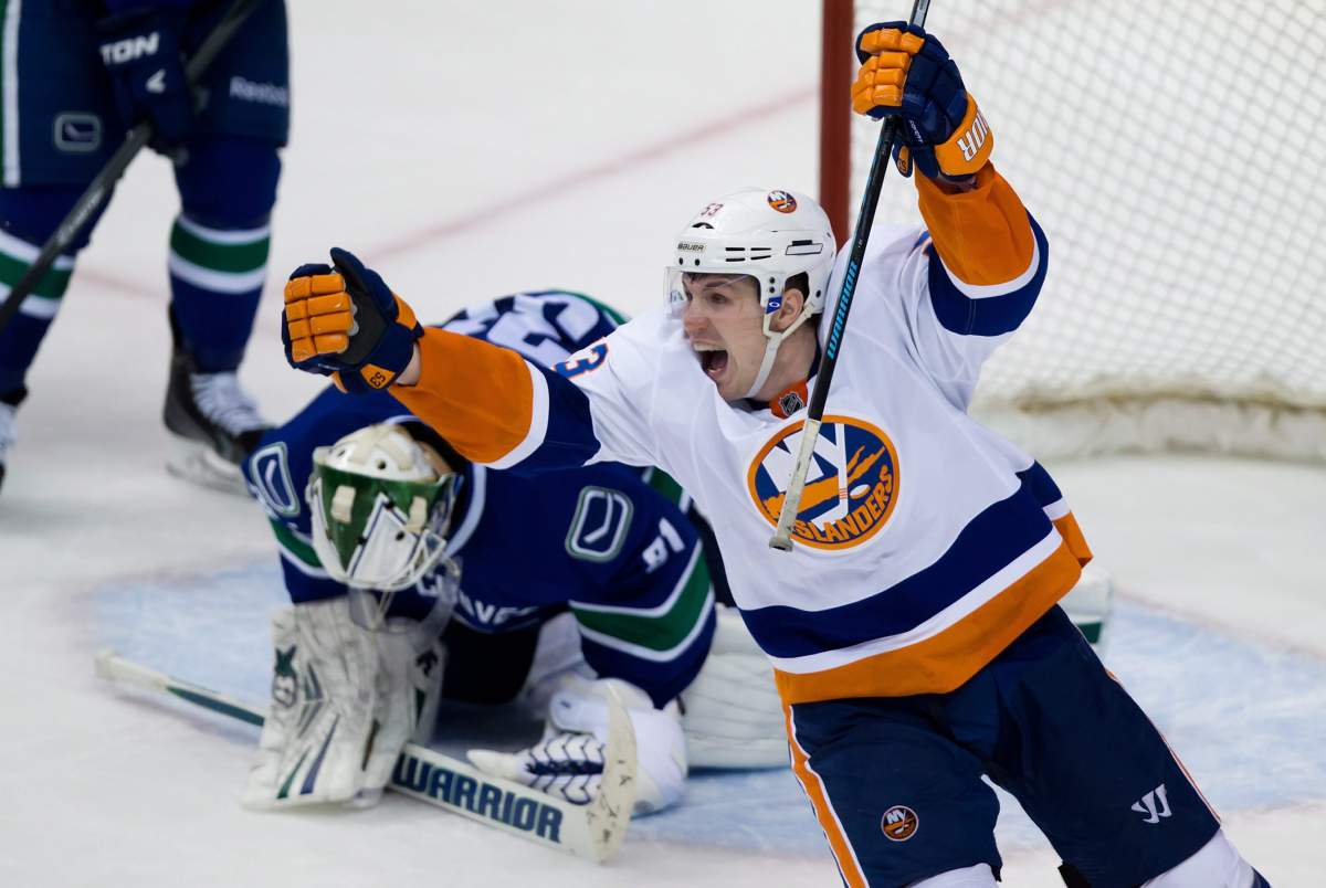 New York Islanders' Casey Cizikas, right, celebrates after Matt Martin scored the team's fifth goal as Vancouver Canucks' goalie Eddie Lack, of Sweden, kneels on the ice during third period NHL hockey action in Vancouver, B.C., on Monday March 10, 2014. THE CANADIAN PRESS/Darryl Dyck.