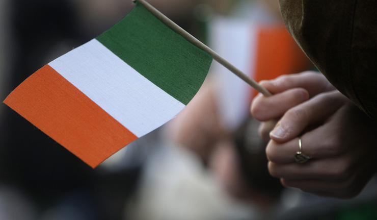 A reveler holds an Irish flag while attending a St. Patrick's Day parade.