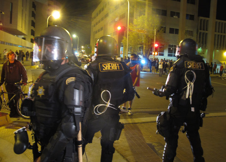 Riot police stand guard in front of protesters in downtown Albuquerque, N.M., Sunday, March 30,2014. 