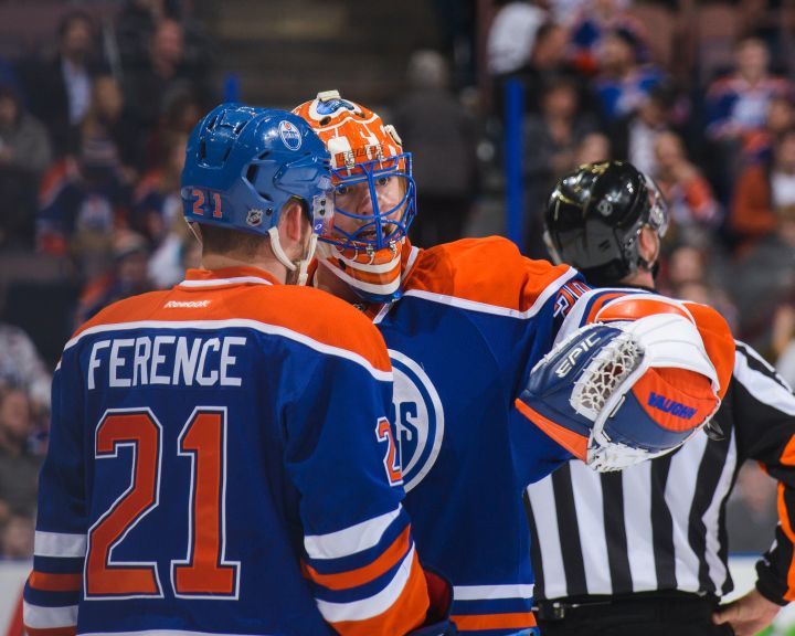 Andrew Ference #21 (L) and Ben Scrivens #30 of the Edmonton Oilers confer between play against the San Jose Sharks during an NHL game at Rexall Place on March 25, 2014 in Edmonton, Alberta, Canada. 