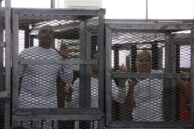 Al-Jazeera English bureau chief Mohamed Fahmy, left, producer Baher Mohamed, center and correspondent Peter Greste, right, appear in a defendant's cage in a courtroom along with several other defendants during their trial on terror charges, in Cairo, Egypt, Monday, March 31, 2014. His family said Friday they have met with Foreign Affairs Minister John Baird.