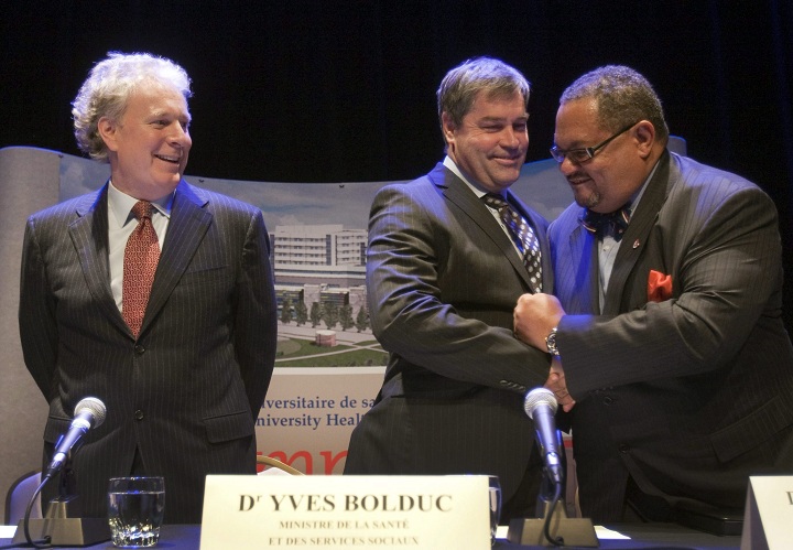 Former Quebec premier Jean Charest, left, looks on as then Health Minister Yves Bolduc and Dr. Arthur Porter congratulate each other at the ground turning ceremonies for the new McGill University Hospital Thursday, April 1, 2010 in Montreal.