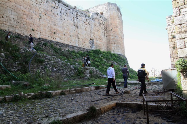 People walk around the Crac des Chevaliers as Syrian troops take reporters on a tour a day after they ousted rebels from the castle located near the village of Hosn, Syria, Friday, March 21, 2014. (AP Photo).