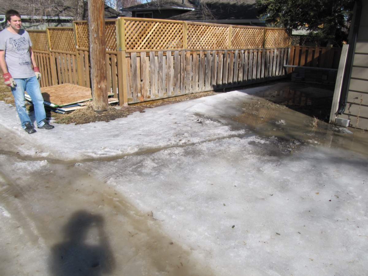 Kyle Dobson surveys a stream of melted snow moving along the alley behind his home.