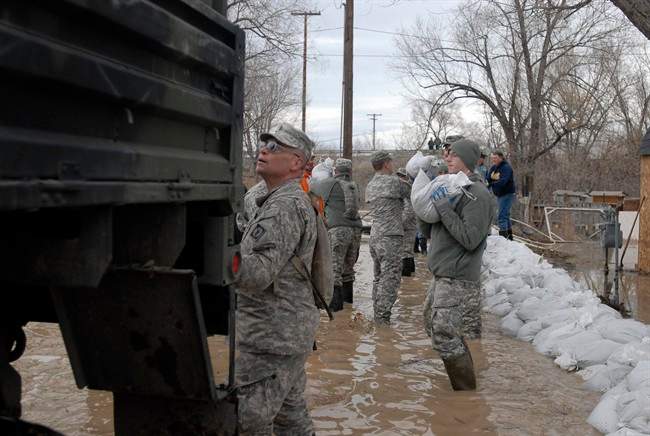 This March 9, 2014 photo provided by the Wyoming National Guard shows Guard members, with the 153rd Airlift Wing and the 920th Forward Support Company, civilian volunteers and town employees forming a chain to deliver sandbags to flooding houses in Graybull, Wyo.