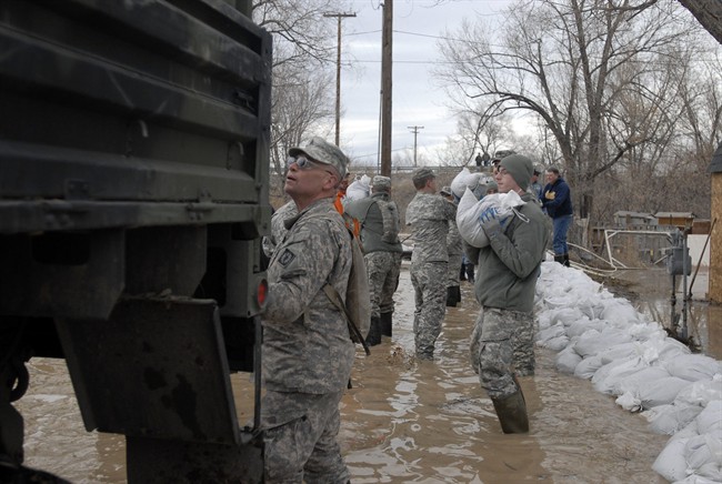 This March 9, 2014 photo provided by the Wyoming National Guard shows Guard members, with the 153rd Airlift Wing and the 920th Forward Support Company, civilian volunteers and town employees forming a chain to deliver sandbags to flooding houses in Graybull, Wyo.
