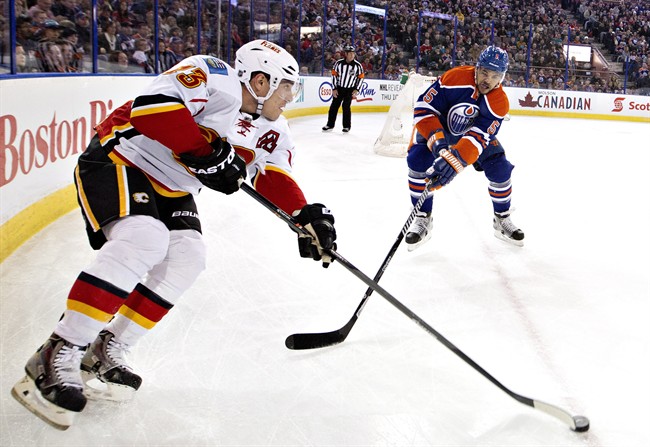 Calgary Flames' Sean Monahan (23) battles in the corner with Edmonton Oilers' Mark Fraser (5) during first period NHL hockey action in Edmonton, Alta., on Saturday March 1, 2014.