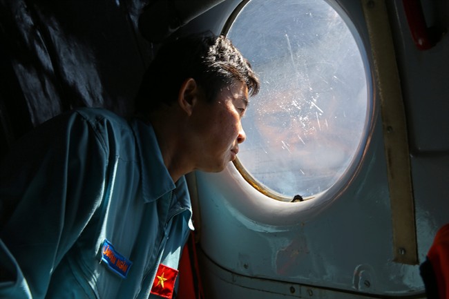 Officer Lang Van Ngan of the Vietnam Air Force looks out the window onboard a flying AN-26 Soviet made aircraft during a search operation for the missing Malaysia Airlines flight MH370 plane over the southern sea between Vietnam and Malaysia Friday, March 14, 2014.