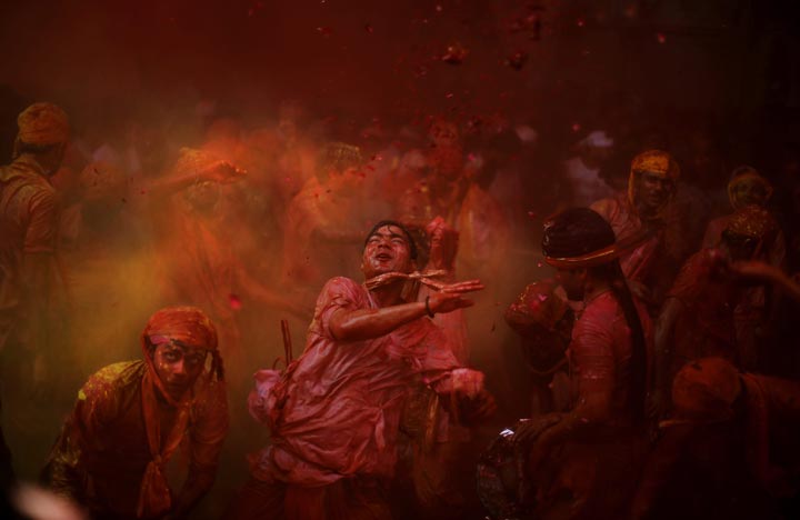 Hindu men from the village of Nangaon throw coloured powder on others as they play Holi at the Radha temple before the procession for the Lathmar Holi festival in Barsana, India. 
