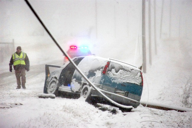 Grant County Sheriff's officers stand by at the scene of an accident on Ind. 26 east of Upland, Ind., as snow falls Wednesday, March 12, 2014.