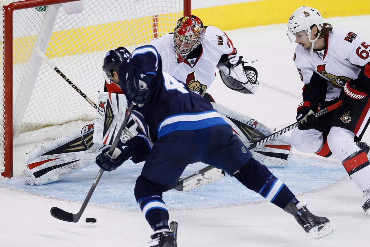 Winnipeg Jets' Devin Setoguchi (40) can't connect on this shot on Ottawa Senators goaltender Craig Anderson (41) as Erik Karlsson (65) covers for the rebound during third period NHL action in Winnipeg on Saturday, March 8, 2014. THE CANADIAN PRESS/John Woods.