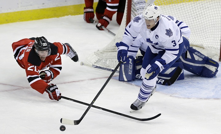 New Jersey Devils' Ryan Carter (20) dives for the puck with Toronto Maple Leafs' Dion Phaneuf (3) during the second period of an NHL hockey game, Sunday, March 23, 2014, in Newark, N.J. 