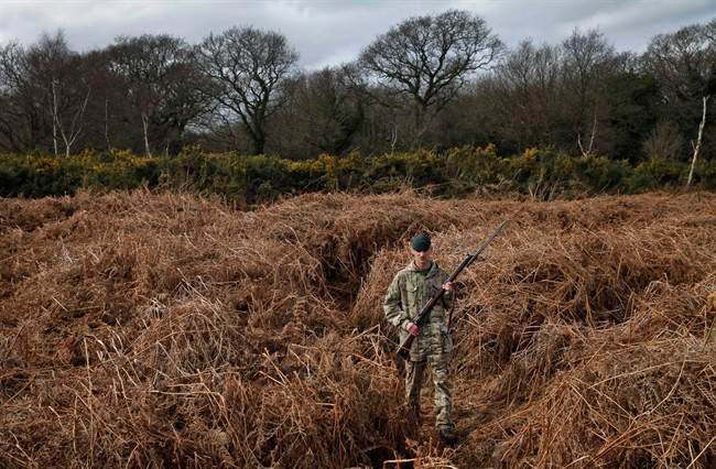 British army Rifleman Stuart Gray walks on a WW1 practise trench as he poses for the photographers in Gosport, southern England, Thursday, March 6, 2014. This overgrown and oddly corrugated patch of heathland on England’s south coast was once a practice battlefield, complete with trenches, weapons and barbed wire. Thousands of troops trained here to take on the Germany army.  (AP Photo/Lefteris Pitarakis).