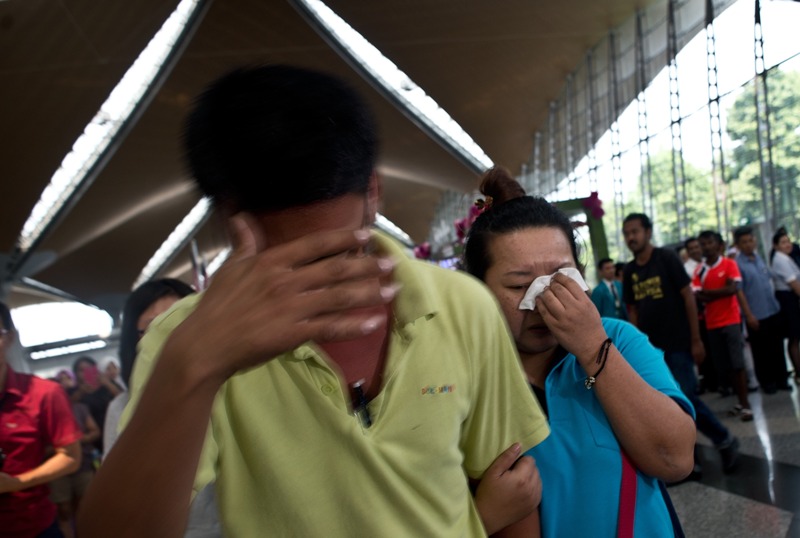 A woman (R) breaks down while leaving the reception centre for families and friends after an airliner went missing at the Kuala Lumpur International Airport on March 8, 2014.