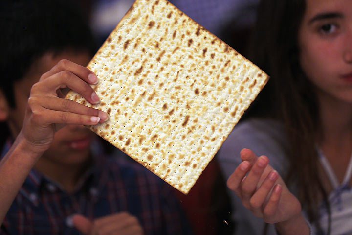 Omri Brandes (L) and Nitzan Brandes eat matzo during a community Passover Seder at Beth Israel synagogue on March 25, 2013 in Miami Beach, Florida.