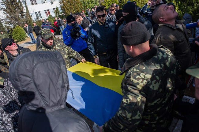 Ukrainian soldiers fold the Ukrainian flag, which was removed by a Crimean pro- Russian self-defence force at the Ukrainian Navy headquarters in Sevastopol, Crimea, on March 19.