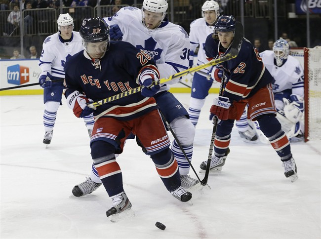 New York Rangers' Martin St. Louis (26) fights for control of the puck with Toronto Maple Leafs' Carl Gunnarsson during the second period of an NHL hockey game Wednesday, March 5, 2014, in New York.