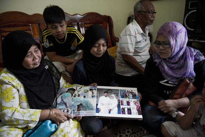 Family members look at a wedding album of Norliakmar Hamid and Razahan Zamani, passengers on a missing Malaysia Airlines Boeing 777-200 plane in Kuala Lumpur on March 8, 2014. (Mohd Rasfan/AFP/Getty Images)