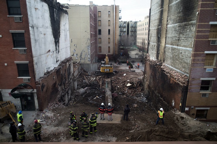 Workers stand beside the recently cleared basement of the two buildings leveled by an explosion on Wednesday in the East Harlem neighborhood of New York, Sunday, March 16, 2014.