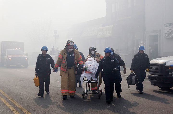 Rescue workers remove an injured person on a stretcher following a building explosion and collapse in East Harlem, Wednesday, March 12, 2014 in New York.