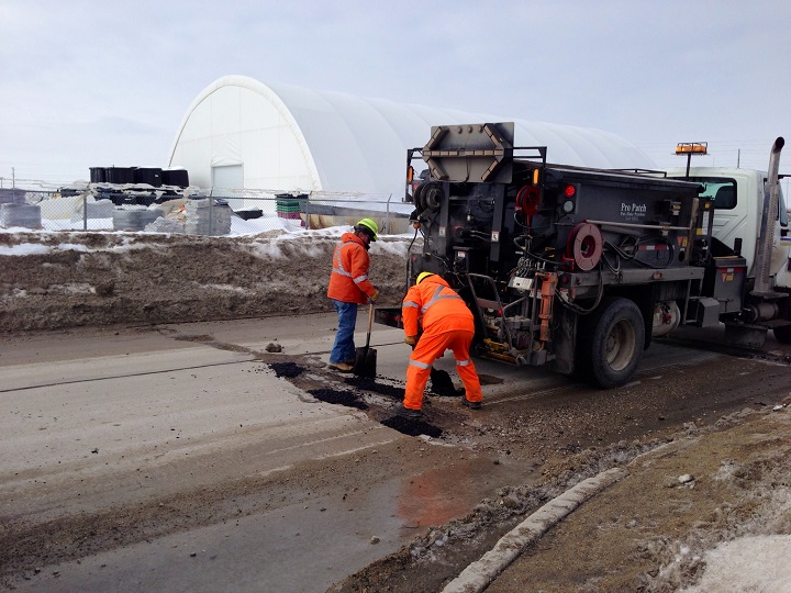 Crews fix potholes on Ravelstone Avenue W. on Tuesday.