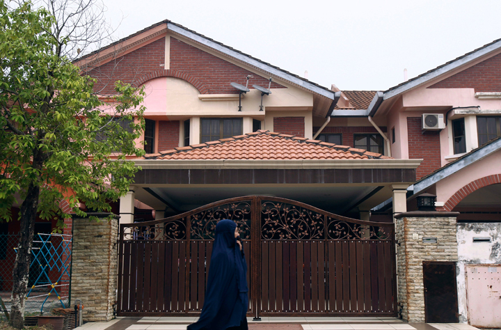 A Muslim woman walks past the missing Malaysia Airlines co-pilot Fariq Abdul Hamid’s house in Shah Alam, outside Kuala Lumpur, Malaysia, Friday, March 14, 2014.