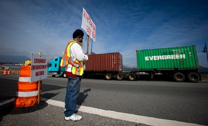 Striking container-truck driver Gajjan Bal holds a sign that reads "Traitors Be Ashamed of Yourself" while standing at a picket line as a truck enters Port Metro Vancouver in Vancouver, B.C., on Thursday March 13, 2014. More than 1,000 container-truck drivers have been on strike since February 26, refusing to work due to low pay and long delays at port terminals. THE CANADIAN PRESS/Darryl Dyck.