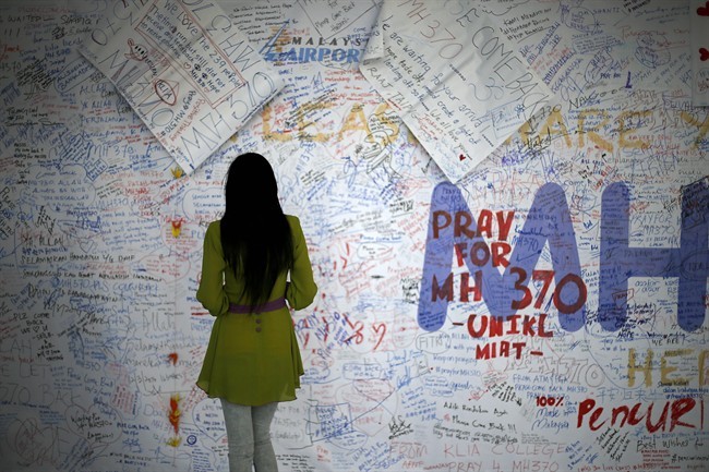A woman reads messages and well wishes to people involved with the missing Malaysia Airlines jetliner MH370, Saturday, March 15, 2014 in Sepang, Malaysia.