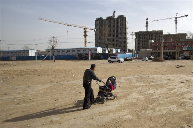 A man pushes a baby buggy near a construction site of a residential real estate project on the outskirts of Beijing on Monday.