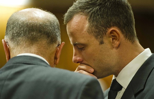 Oscar Pistorius, right, talks with his uncle Arnold Pistorius in court on the fifth day of his trial at the high court in Pretoria, South Africa, Friday, March 7, 2014. Pistorius is charged with murder for the shooting death of his girlfriend, Reeva Steenkamp, on Valentines Day in 2013. (AP Photo/Theana Breugem, Pool).