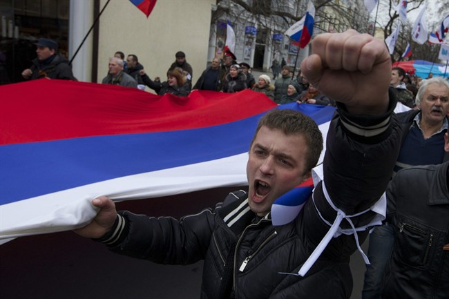 Local residents carry Russian flags and shout slogans rallying over the streets of Crimean capital Simferopol, Ukraine, on Saturday, March 1, 2014. Russian President Vladimir Putin asked parliament Saturday for permission to use the country’s military in Ukraine, moving to formalize what Ukrainian officials described as an ongoing deployment of Russian military on the country’s strategic region of Crimea.