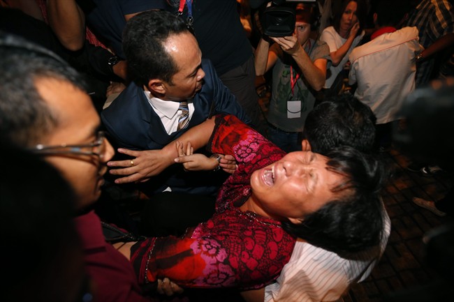 A Chinese relative of a passenger aboard a missing Malaysia Airlines plane is carried out by security officials as she protests before a press conference at a hotel in Sepang, Malaysia, Wednesday, March 19, 2014.